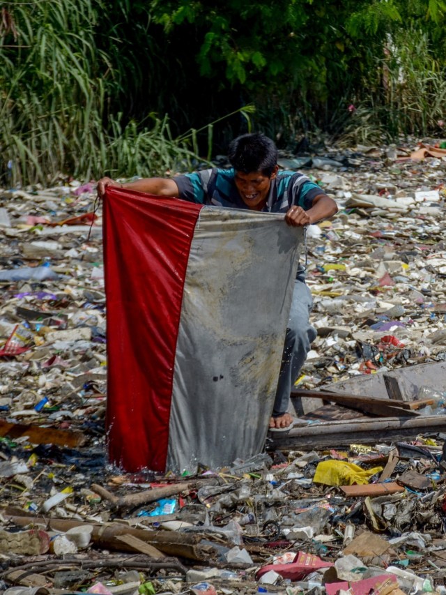 Warga menemukan bendera merah putih di antara sampah yang menutupi Sungai Citepus yang bermuara ke Sungai Citarum di Bojong Soang, Dayeuhkolot, Bandung. Foto: ANTARA FOTO/Raisan Al Farisi