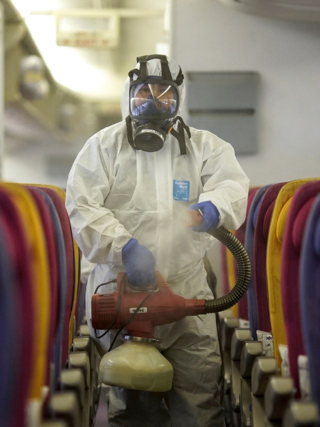 Seorang kru Thai Airways mendisinfeksi kabin pesawat nasional untuk mencegah penyebaran coronavirus di Bandara Internasional Suvarnabhumi, Bangkok. Foto: REUTERS/Athit Perawongmetha
