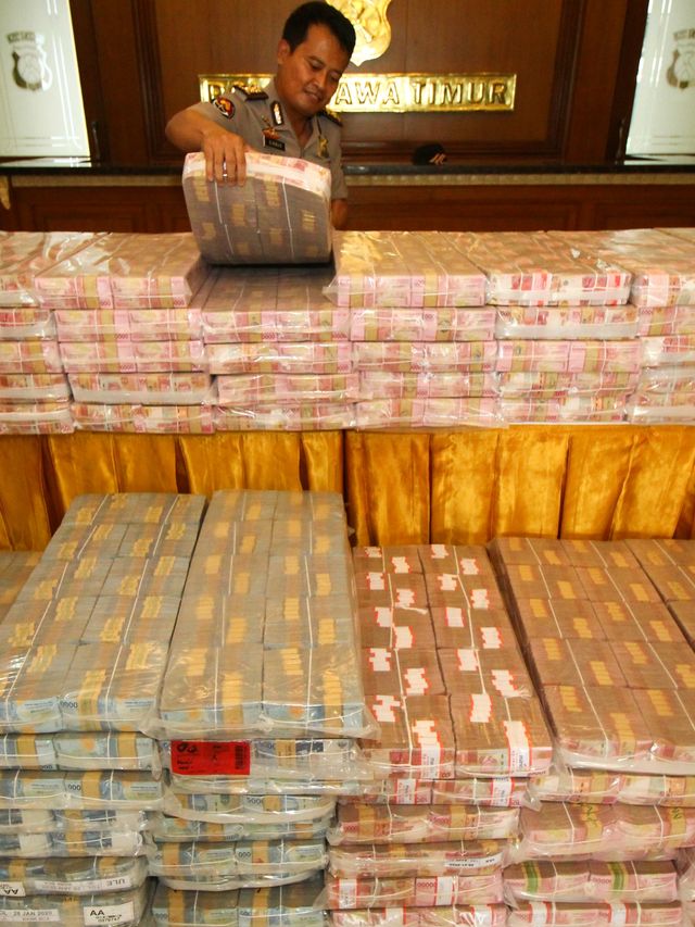 Polisi menata barang bukti uang tunai rupiah kasus investasi ilegal 'MeMiles' di Polda Jawa Timur, Surabaya, Jawa Timur, Selasa (28/1).  Foto: ANTARA FOTO/Didik Suhartono