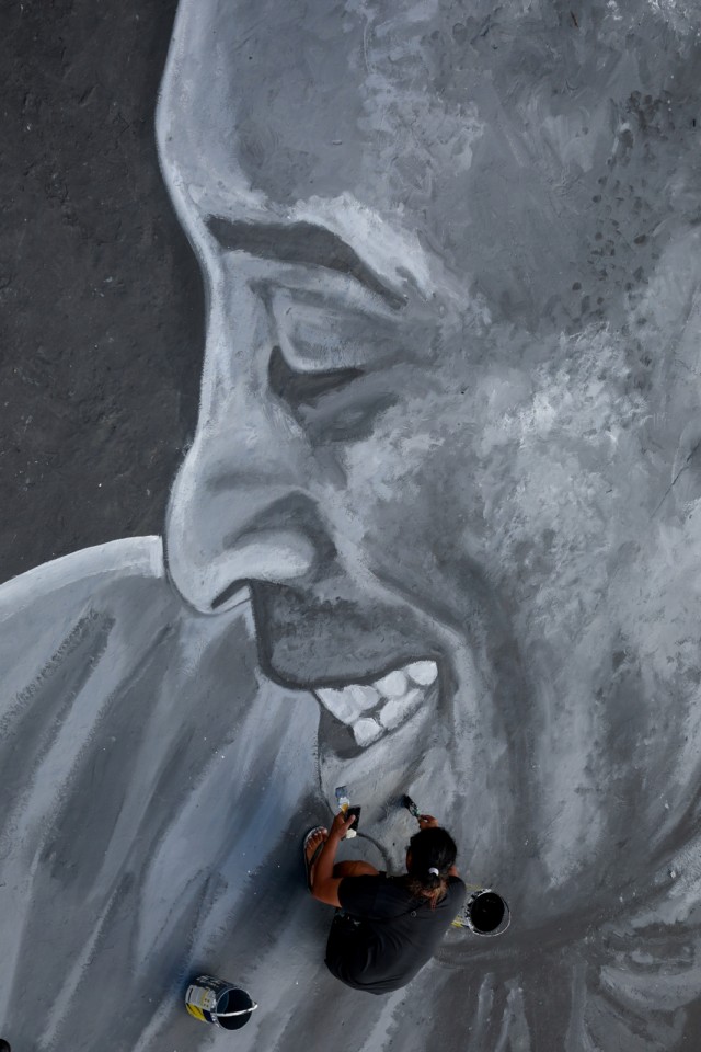 Seorang pria melihat pembuatan mural untuk mengenang Kobe Bryant dan putrinya, Gianna, di lapangan bola basket perumahan Taguig City, Metro Manila, Filipina. Foto: REUTERS/Eloisa Lopez