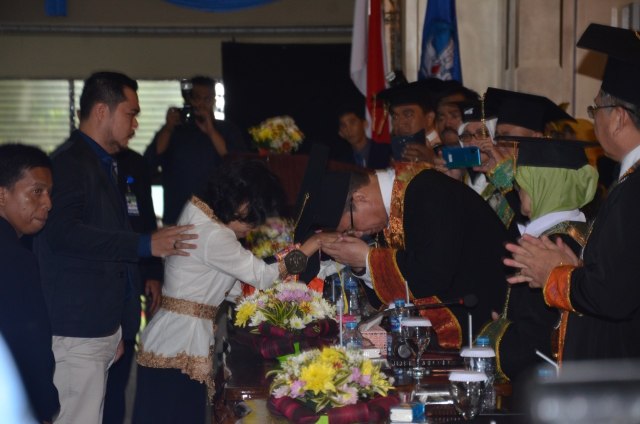 Rektor Universitas Tanjungpura, Garuda Wiko, mencium tangan Marcieny, yang mewakili almarhum anaknya untuk diwisuda. Foto: Dok Untan