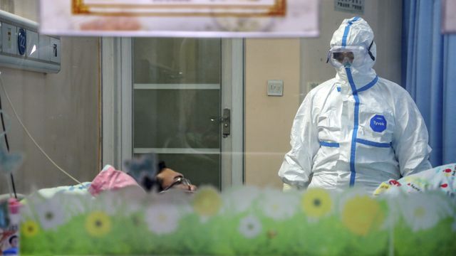 Seorang dokter mengenakan pakaian pelindung merawat warga yang terkena virus corona. Foto: Chinatopix via AP