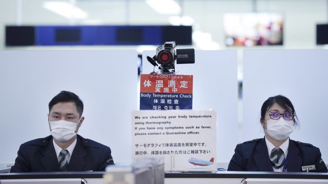 Petugas menggunakan masker memeriksa penumpang dari Wuhan China di Bandar Udara Internasional Narita, Tokyo.  Foto: STR / JIJI PRESS / AFP