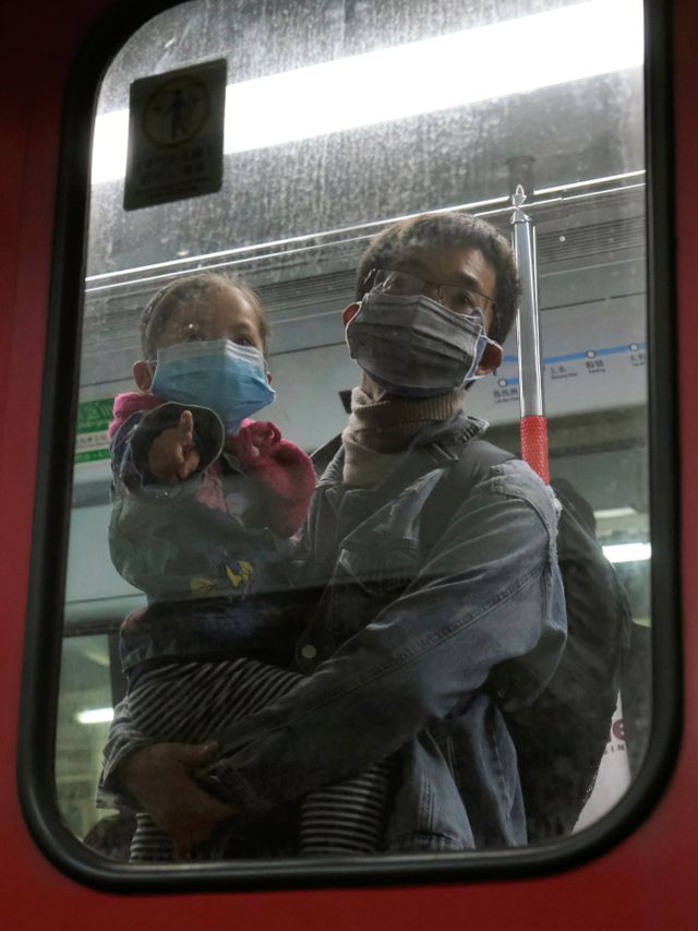 Seorang pria menggendong anaknya di dalam gerbong MRT beberapa jam sebelum penutupan pintu perbatasan dengan China, Senin (3/2). Foto: REUTERS / Tyrone Siu