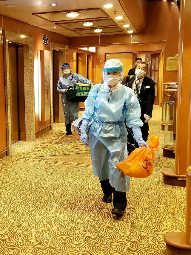 Petugas menggunakan pakaian pelindung berada di atas dek kapal pesiar Diamond Princess yang dikarantina di pelabuhan Yokohama, Jepang, Selasa (4/2). Foto: Twitter / @DAXA_TW via REUTERS