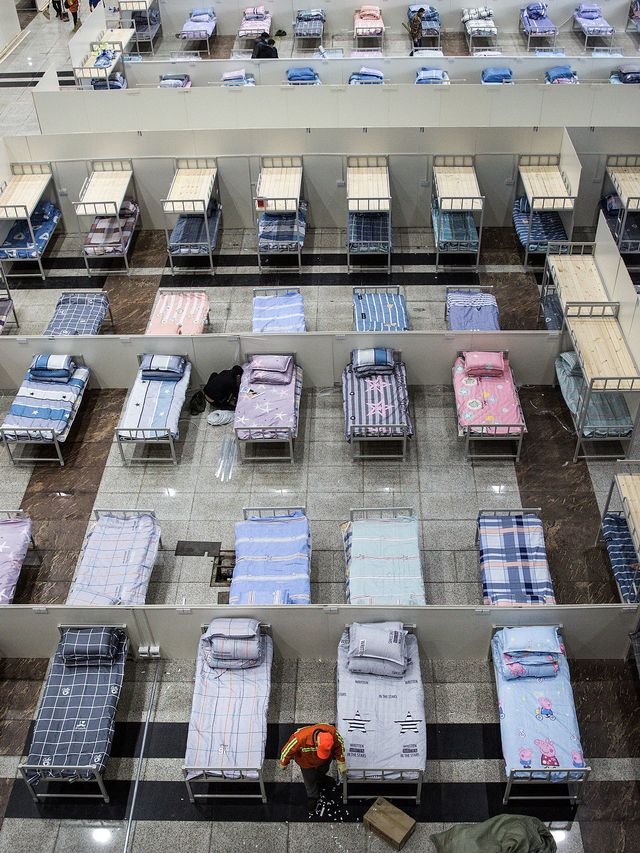 Para pekerja menyiapkan tempat tidur di Pusat Konferensi dan Pameran Internasional Wuhan yang di ubah jadi rumah sakit. Foto: Getty Images