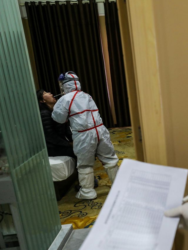 Petugas medis memeriksa pasien yang diduga terkena virus corona di tempat karantina di Wuhan, China. Foto: STR / AFP