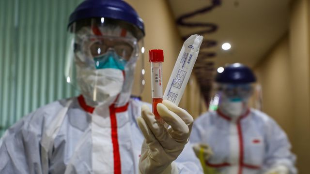 Petugas medis menunjukkan sampel yang diambil dari pasien yang diduga terkena virus corona di tempat karantina di Wuhan, China. Foto: STR / AFP