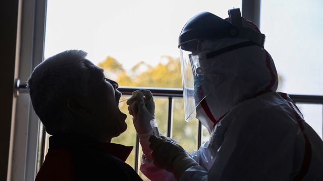 Petugas mengambil sampel dari pasien yang diduga terkena virus corona di tempat karantina di Wuhan, China. Foto: STR / AFP