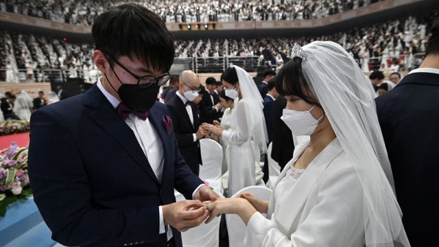 Pasangan pengantin menggunakan masker menghadiri pernikahan massal di Cheongshim Peace World Center, Gapyeong, Korea Selatan.  Foto: AFP/Jung Yeon-je