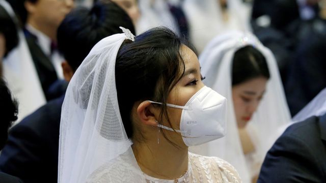 Pengantin wanita menggunakan masker menghadiri pernikahan massal di Cheongshim Peace World Center, Gapyeong, Korea Selatan.  Foto: REUTERS / Heo Ran