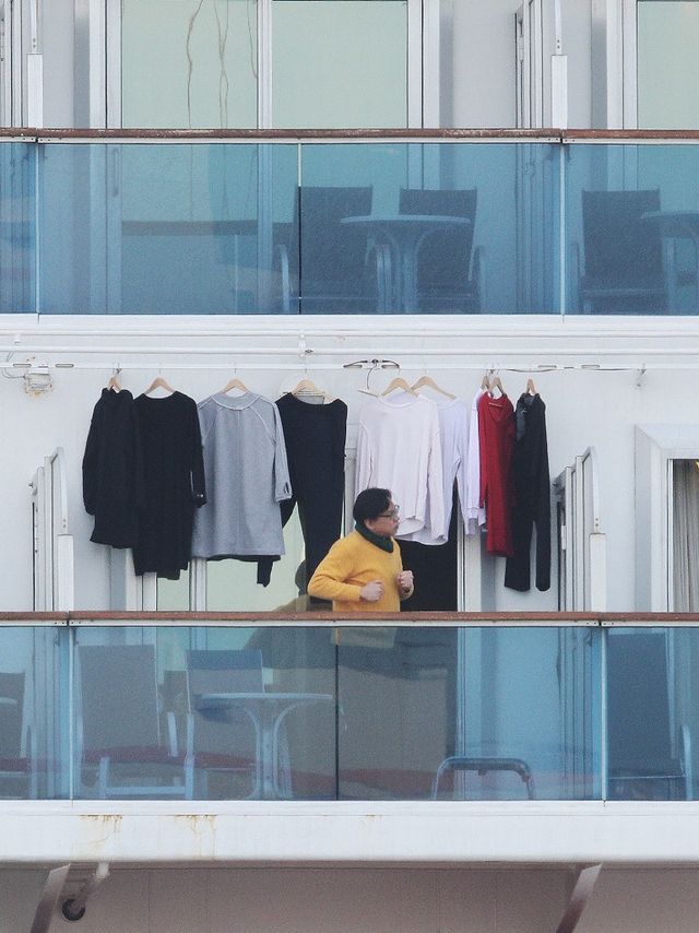 Penumpang kapal pesiar Diamond Princess berdiri di balkon usai menjemur pakaian saat menjalani karantina di Daikoku Pier Cruise Terminal, Yokohaman, Jepang. Foto: AFP/JIJI PRESS