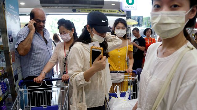 Orang-orang menunggu stok masker pelindung di apotek di Singapura. Foto: REUTERS/Feline Lim