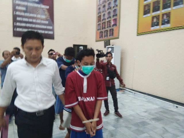 Tersangka Heri Candra (baju merah) saat digelandang petugas untuk diekspose di Gedung Graha Wiyono Siregar Mapolda Lampung, Senin (10/2) | Foto: Obbie Fernando/Lampung Geh