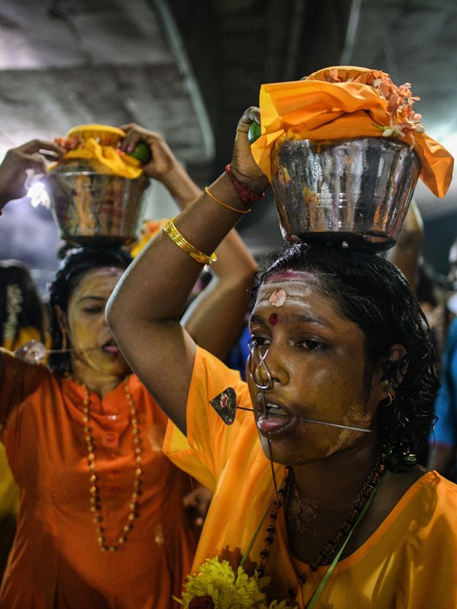 Umat Hindu membawa pot susu di kepala mereka sebagai persembahan saat berjalan menuju di Kuil Batu Caves saat Festival Thaipusam di Kuala Lumpur, Malaysia. Foto: Mohd RASFAN / AFP