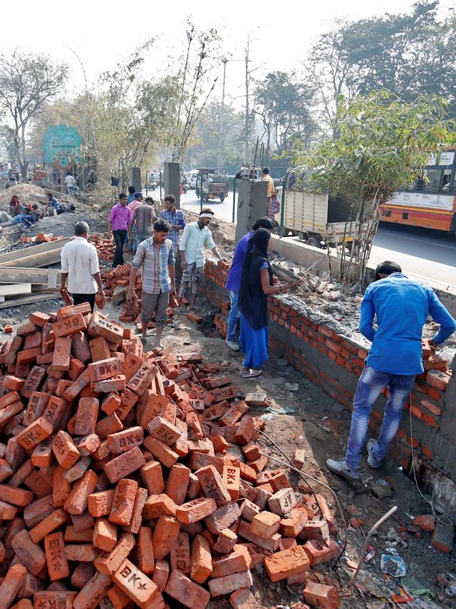 Sejumlah pekerja menyelasaikan bangunan tembok di sepanjang jalan yang akan dilalui Presiden Amerika Serikat Donald Trump di Ahmedabad, India, Kamis (13/2). Foto: REUTERS / Amit Dave