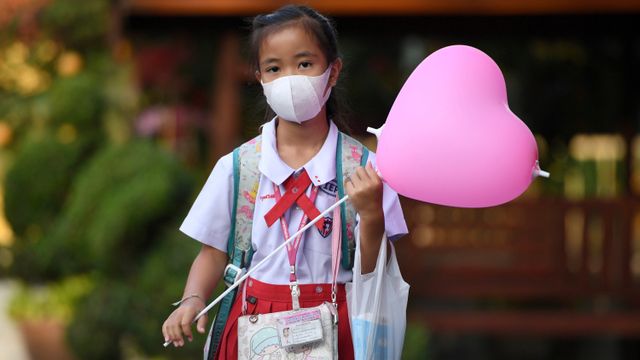 Seorang siswa menggunakan masker membawa balon bentuk hati pada hari valentine di Ayutthaya, Bangkok, Thailand. Foto: REUTERS / Chalinee Thirasupa