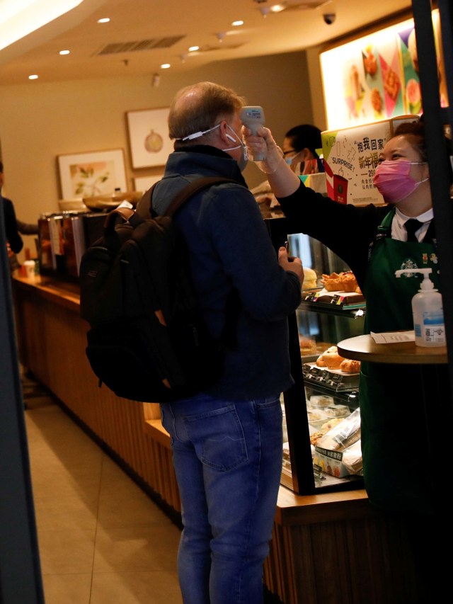 Barista Starbucks memeriksa suhu badan pengunjung akibat virus corona di Beijing, China. Foto: REUTERS/Carlos Garcia Rawlins
