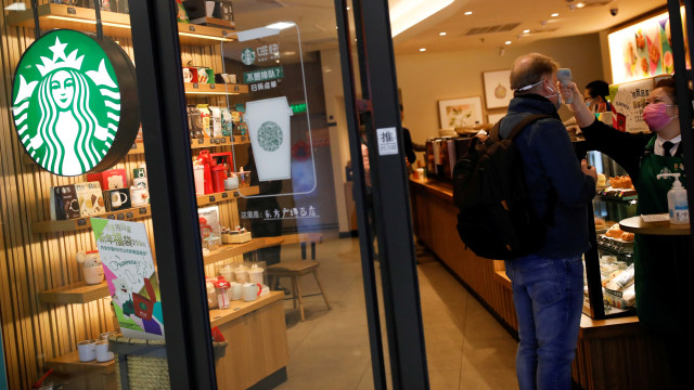 Barista Starbucks memeriksa suhu badan pengunjung akibat virus corona di Beijing, China. Foto: REUTERS/Carlos Garcia Rawlins