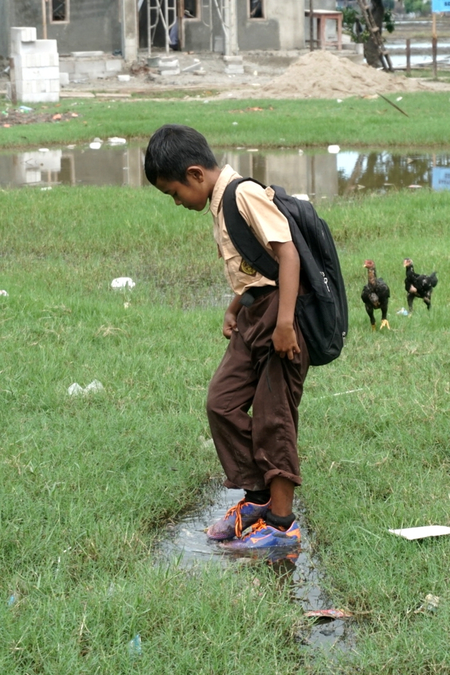 Siswa SDN Samudera Jaya 4 Bekasi melintasi lapangan yang tergenang air.
 Foto: Iqbal Firdaus/kumparan