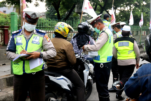 Polisi menilang pemotor yang menerobos jalur TransJakarta di kawasan Pasar Rumput. Foto: Iqbal Firdaus/kumparan