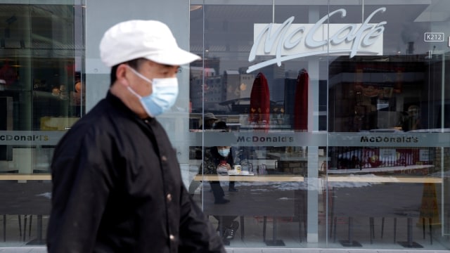seorang warga berjalan menggunakan maskerakibat virus corona di distrik pusat bisnis beijing. FOTO : REUTERS/Jason Lee