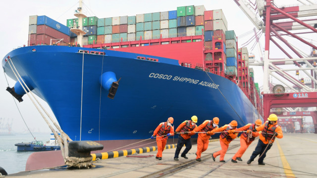 Sejumlah pekerja menggunakan masker mengikatkan sebuah kapal kontainer di Pelabuhan Qindao, Shandong, China. Foto: China Daily / via REUTERS