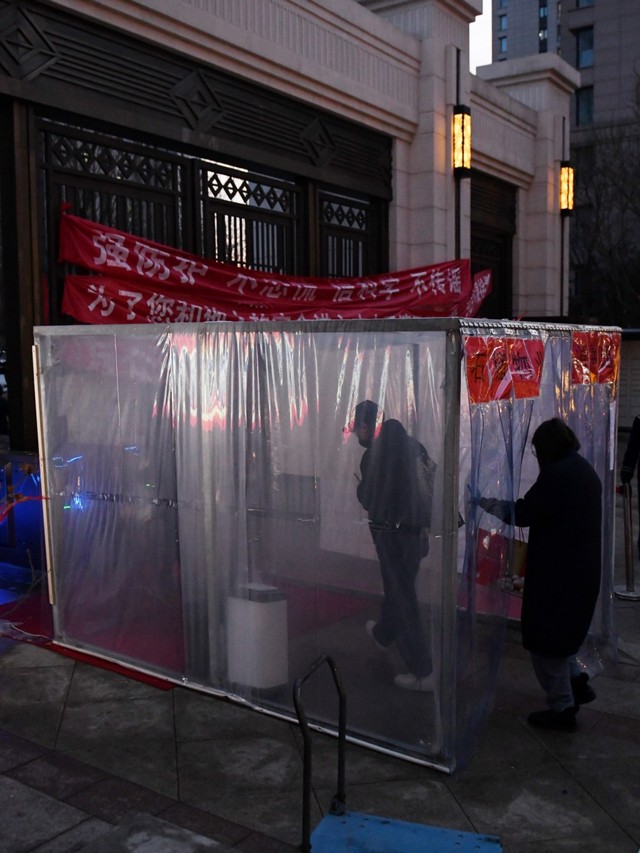 Warga berjalan melewati alat penyemprot disinfektan sebagai upaya perlindungan terhadap virus corona atau COVID-19 di Tongzhou, Beijing, China. Foto: AFP/GREG BAKE