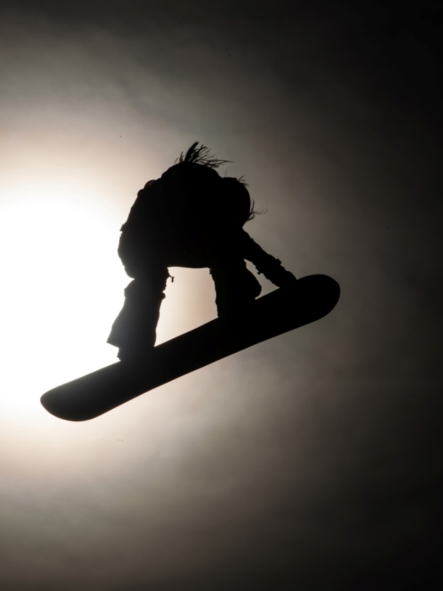 Foto siluet seorang atlet snowboard saat bertanding. Foto: JEFF PACHOUD / AFP