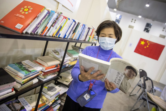 Pasien gejala virus corona atau COVID-19 ringan membaca buku di rumah sakit darurat pusat pameran di Wuhan, Hubei, China.  Foto: AFP/STR