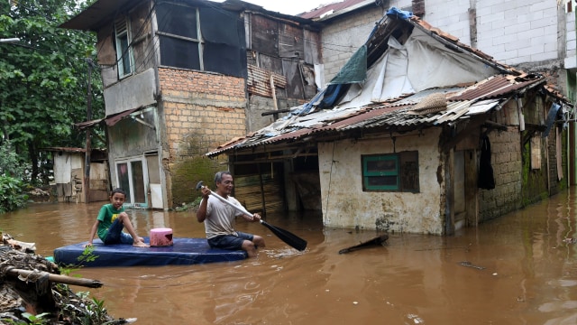 Warga menggunakan perahu buatannya untuk menyusuri jalan perkampungan yang tergenang banjir luapan air Sungai Ciliwung di Cawang, Jakarta, Kamis (20/2). Foto: ANTARA FOTO/Aditya Pradana Putra