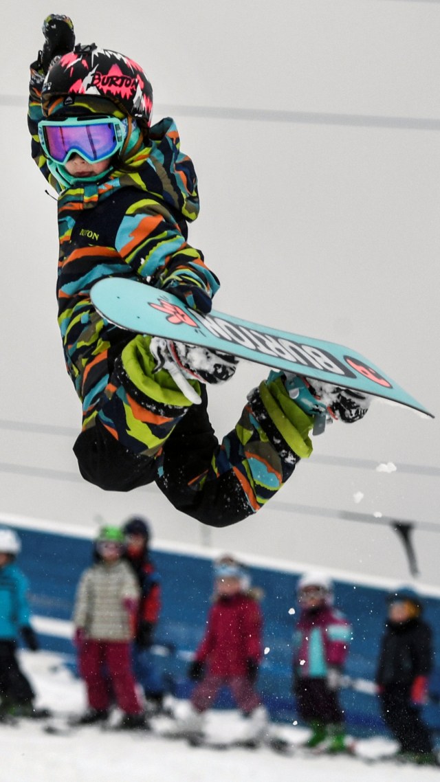 Pemain snowboard Rusia, Vasilisa Ermakova, beraksi saat melewati lompatan di gundukan es, saat berlatih di Moskow. Foto: AFP/ALEXANDER NEMENOV