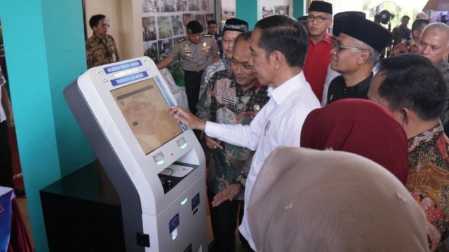 Presiden Joko Widodo (tengah) mencoba mesin Anjungan Dukcapil Mandiri (ADM) di Sekolah Sukma Bangsa, Bireuen, Aceh, Sabtu (22/2). Foto: Dok. Kemendagri