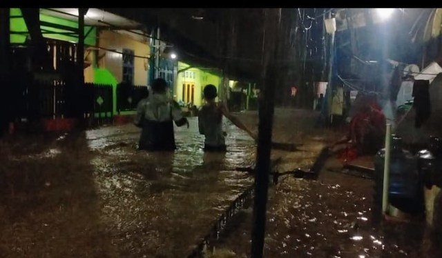 Tampak warga di Kompleks Maduraja melintasi banjir,foto: Edi Musahidin