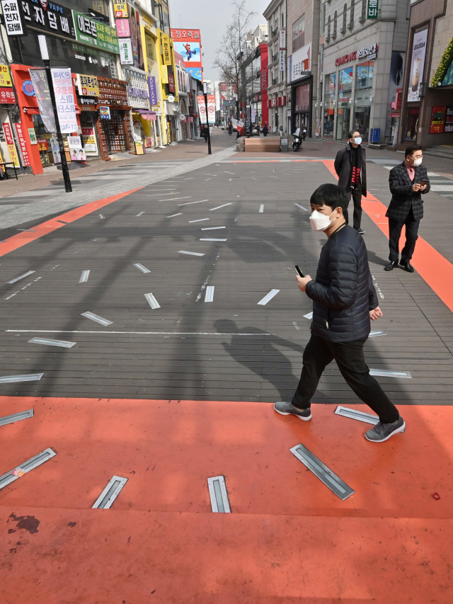 Pejalan kaki mirus Corenggunakan masker melintasi distrik perbelanjaan Dongseongro di kota Daegu, Korea Selatan. Foto: AFP/JUNG YEON-JE
