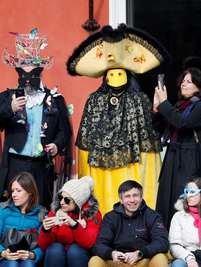 Masyarakat mengenakan topeng saat menonton Karnaval Venesia di Grand Canal, Venesia, Italia, Minggu (9/2).  Foto: REUTERS / Guglielmo Man