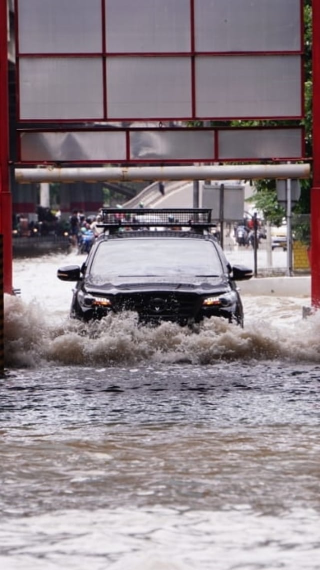 Mobil melintasi Gerbang tol Cempaka Putih, yang tergenang banjir, Minggu (23/2). Foto: Jamal Ramadhan/kumparan