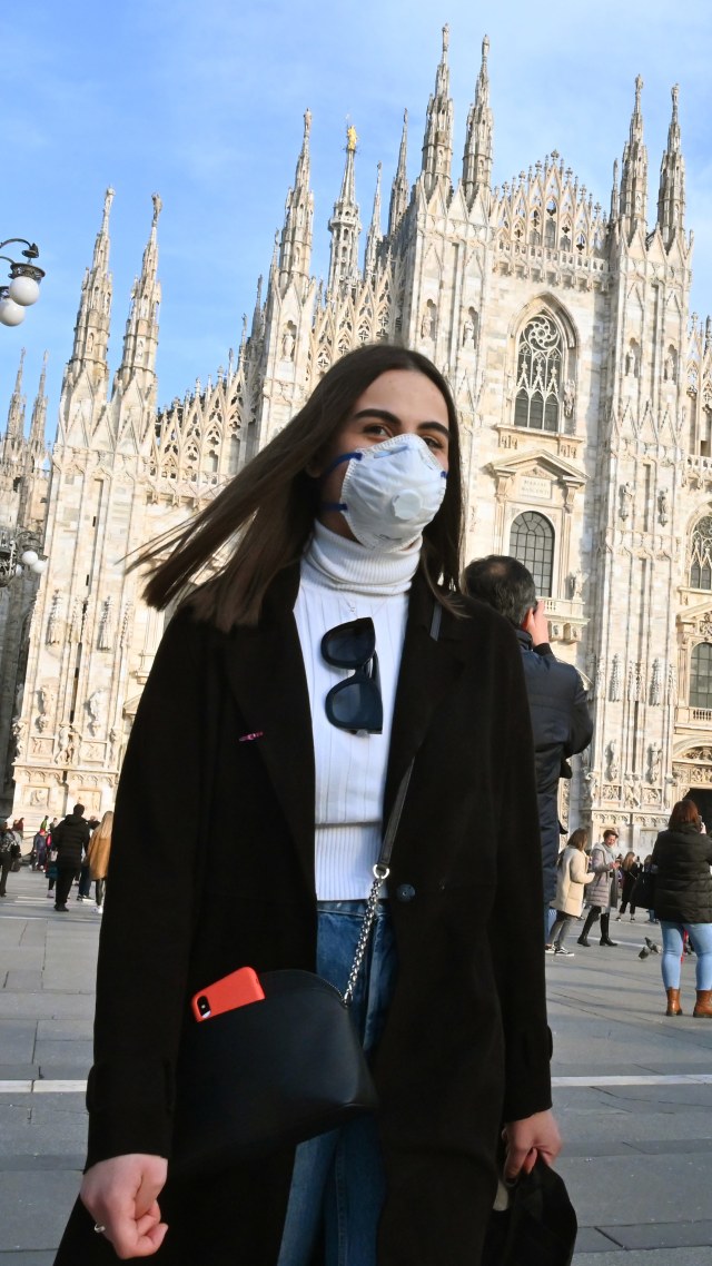 Pengunjung menggunakan masker pernapasan saat melintas di Piazza del Duomo di Milan. Foto: Andreas Solaro / AFP