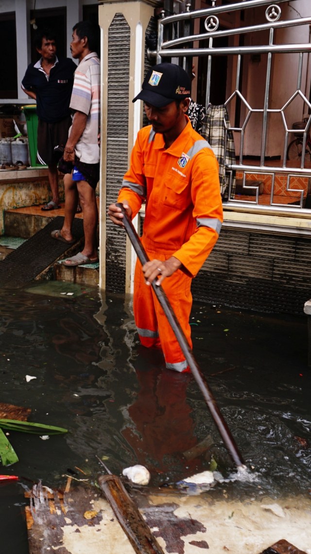 Seorang petugas PPSU beraktivitas saat banjir di RW 03 Kelurahan Pegangsaan Dua, Kecamatan Kelapa Gading, Jakarta Utara, Senin (24/2). Foto: Jamal Ramadhan/kumparan