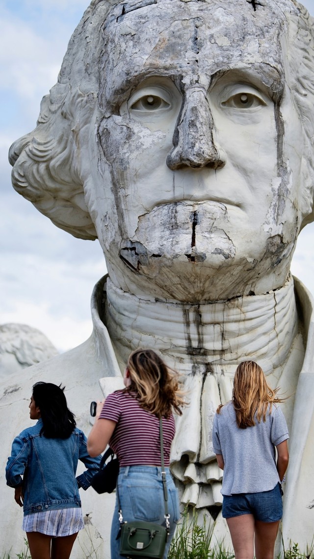 Tiga orang pengunjung beraktivitas di sekitar patung di President Park, Virginia, Amerika Serikat. Foto: Brendan Smialowski / AFP