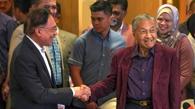 Perdana Menteri Malaysia Mahathir Mohamad (kanan), bersalaman dengan penggantinya Anwar Ibrahim di Putrajaya, Malaysia. Foto: AP Photo/Vincent Thian