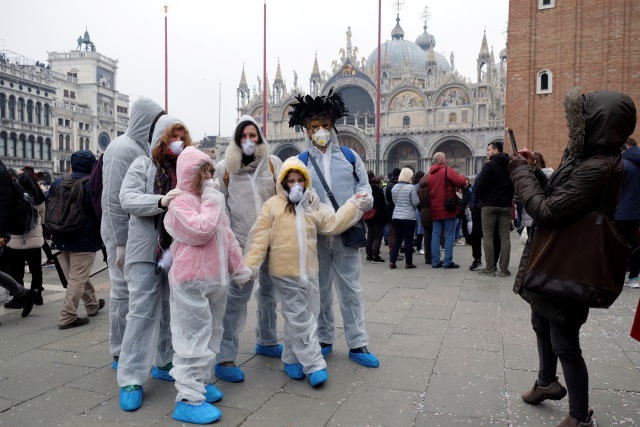 Sejumlah wisatawan mengenakan pakaian pelindung berfoto di Karnaval Venesia, Italia, Minggu (24/2). Foto: REUTERS/Ohad Zwigenberg ISRAEL OUT