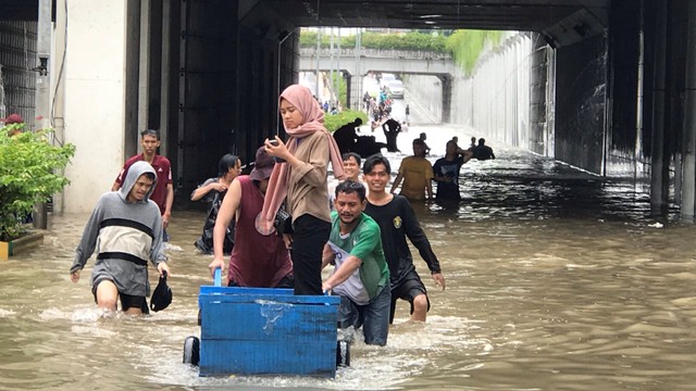 Warga melintasi banjir menggunakan gerobak di kawasan underpass Gunung Sahari, Jakarta, Selasa (25/2).  Foto: Dok. Wiji Nurhayat