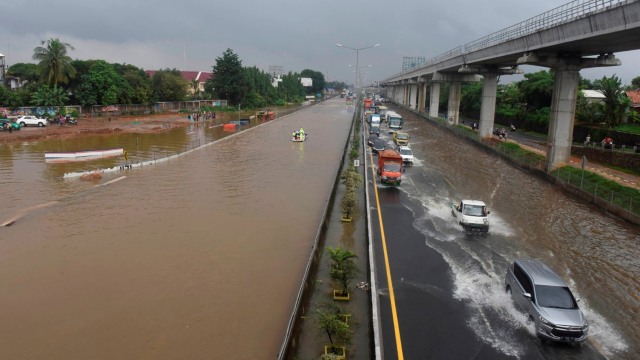 Kendaraan melintasi genangan air sementara ruas lainnya tidak dapat dilintasi akibat banjir di ruas tol Jakarta-Cikampek di Jatibening, Bekasi, Selasa (25/2). Foto: ANTARA FOTO/Saptono