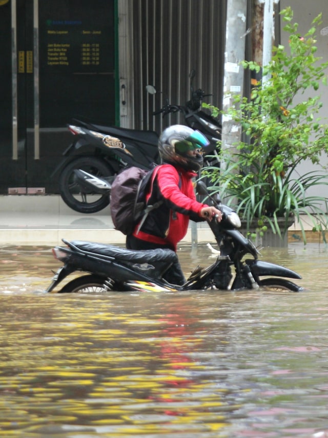 Warga mendorong motornya yang mogok di sekitar Kelapa Gading, Jakarta Utara. Foto: Nugroho Sejati/kumparan