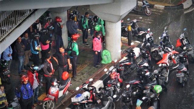 Suasana Jalan Gatot Subroto ketika dilanda hujan, pengendara berteduh di bawah JPO. Foto: Iqbal Firdaus/kumparan