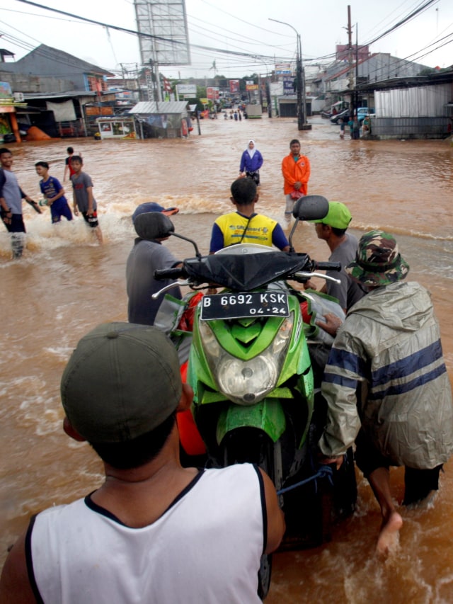 Pengendara sepeda motor menggunakan jasa gerobak saat melintasi banjir di Perumahan Bumi Naseo Indah, Jati Asih, Bekasi, Jawa Barat, Selasa (25/2).  Foto: ANTARA FOTO/Yulius Satria Wijaya