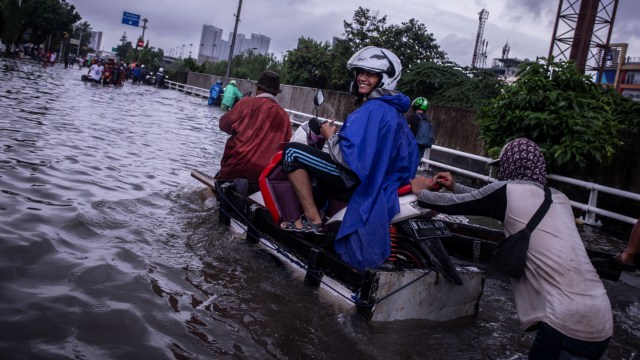 Pengendara sepeda motor menggunakan jasa angkut gerobak saat melintasi banjir di kawasan Grogol, Jakarta, Selasa (25/2).  Foto: ANTARA FOTO/Aprillio Akbar