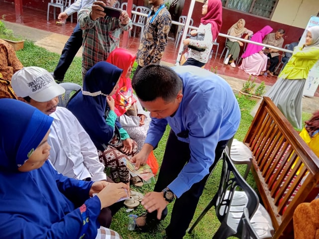 Salah satu petugas dari BI Lampung membantu penyandang tuna netra untuk mengenali uang kertas rupiah dengan cara diraba, Rabu (26/2) | Foto : Sidik Aryono/ Lampung Geh