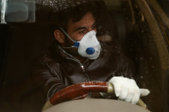 Warga Iran mengenakan masker dan sarung tangan untuk mencegah tertularnya virus corona, saat berkendara. Foto: WANA/Nazanin Tabatabaee via REUTERS